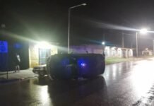 Accidente entre dos autos en Malvinas Argentinas: uno volcó y no hubo heridos Automóvil volcado sobre una calle mojada durante la noche, junto a otro vehículo y luces de emergencia