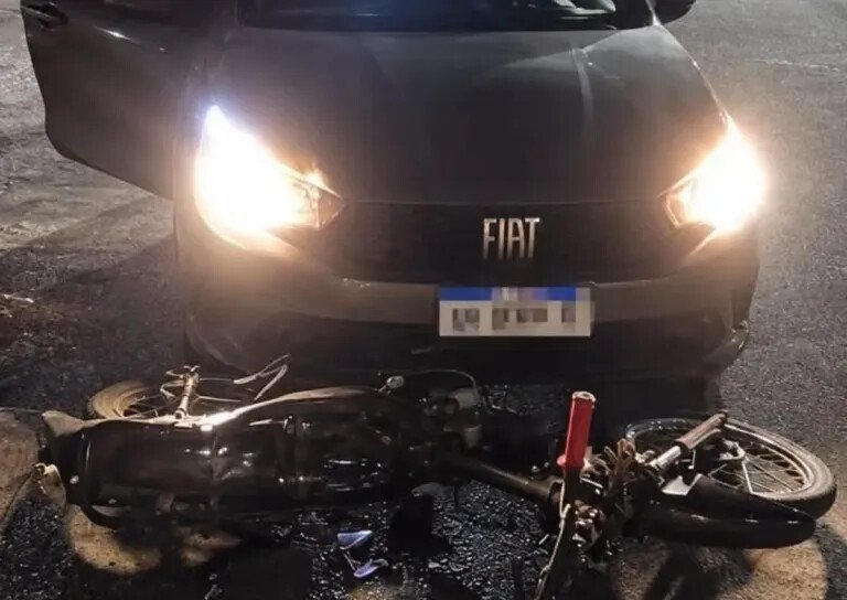Automóvil Fiat detenido con las luces encendidas y una motocicleta caída delante