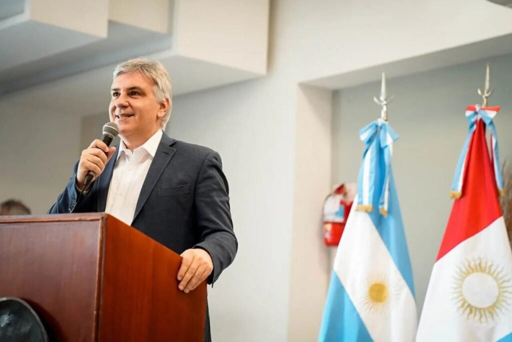 El gobernador habla detrás de un atril acompañado por banderas oficiales